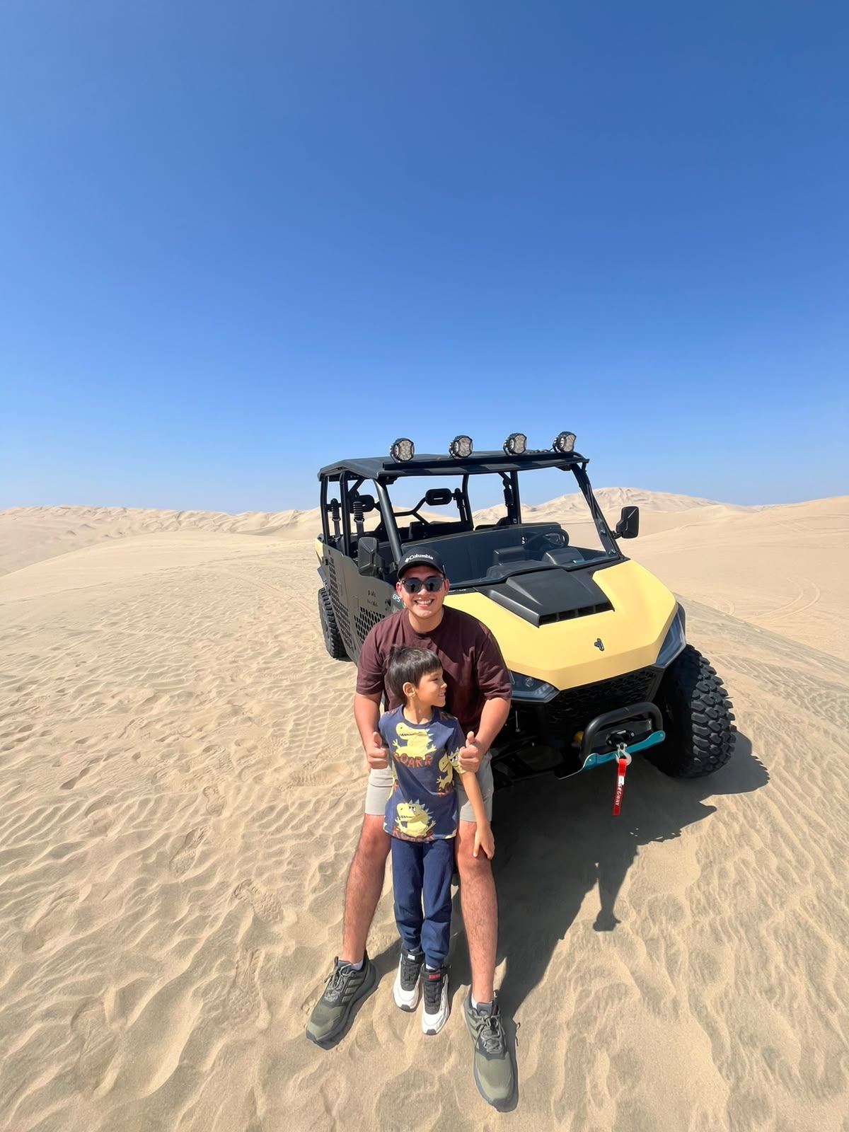 Padre e hijo junto a un UTV en medio del desierto de Ica